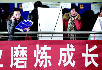 两名研究生在招聘会现场,招聘会上打出“磨练成长”的条幅(资料图)。本报记者　张晓科　摄